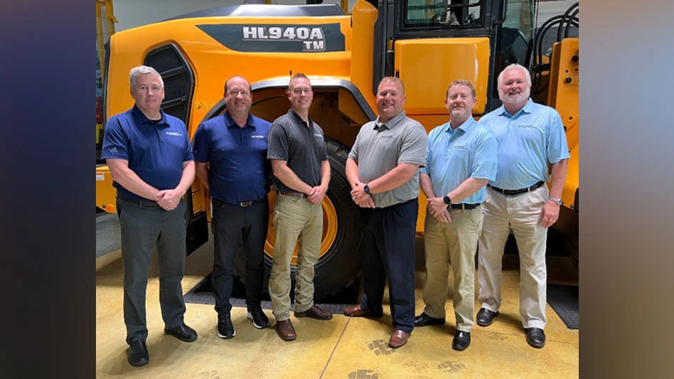 six men stand in front of a hyundai wheel loader