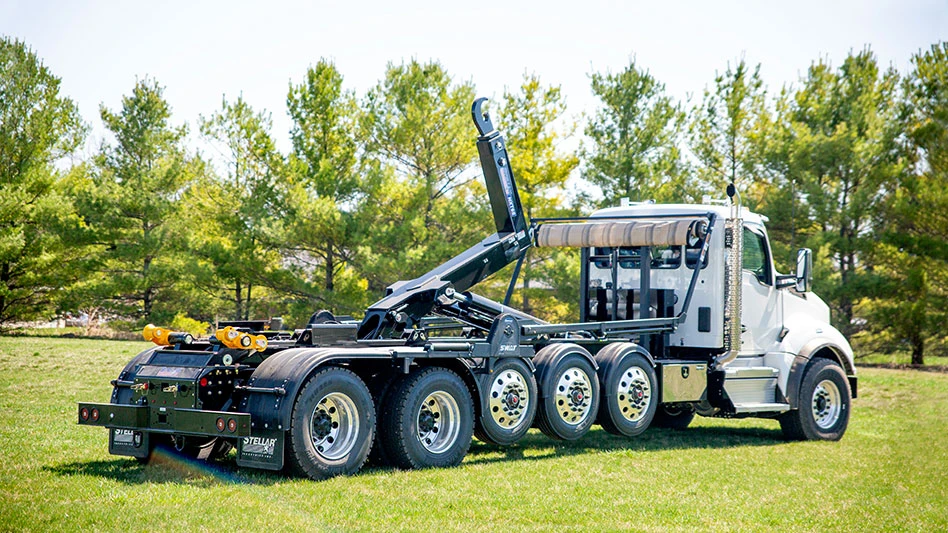 the stellar nxt68 hooklift in a field with trees behind it