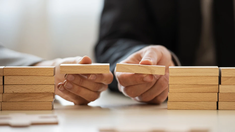 two men in suits stack blocks to make a bridge