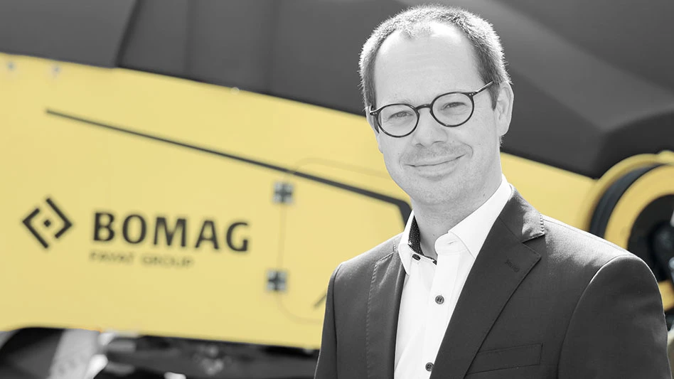 photo of white man in glasses smiling in front of bomag equipment